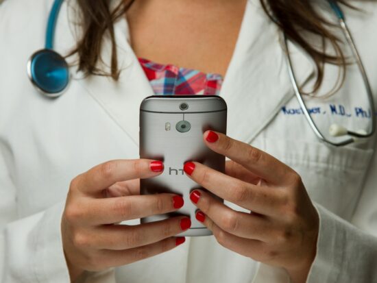 Doctor Holding Cell Phone. Cell phones and other kinds of mobile devices and communications technologies are of increasing importance in the delivery of health care. Photographer Daniel Sone